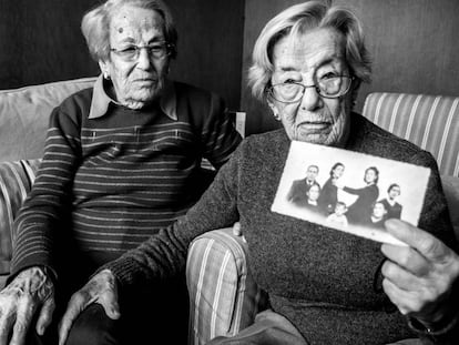 Las hermanas Lucía y Juana Molina Casado, que tienen 100 años, muestran un montaje fotográfico hecho para integrar en el retrato a los familiares ausentes.
