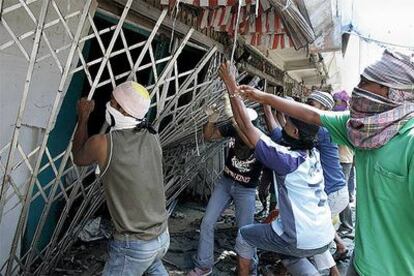 Un grupo de hombres intenta arrancar la verja de una tienda  destruida por el maremoto en Aceh para rescatar mercancías que pueden ser de utilidad.