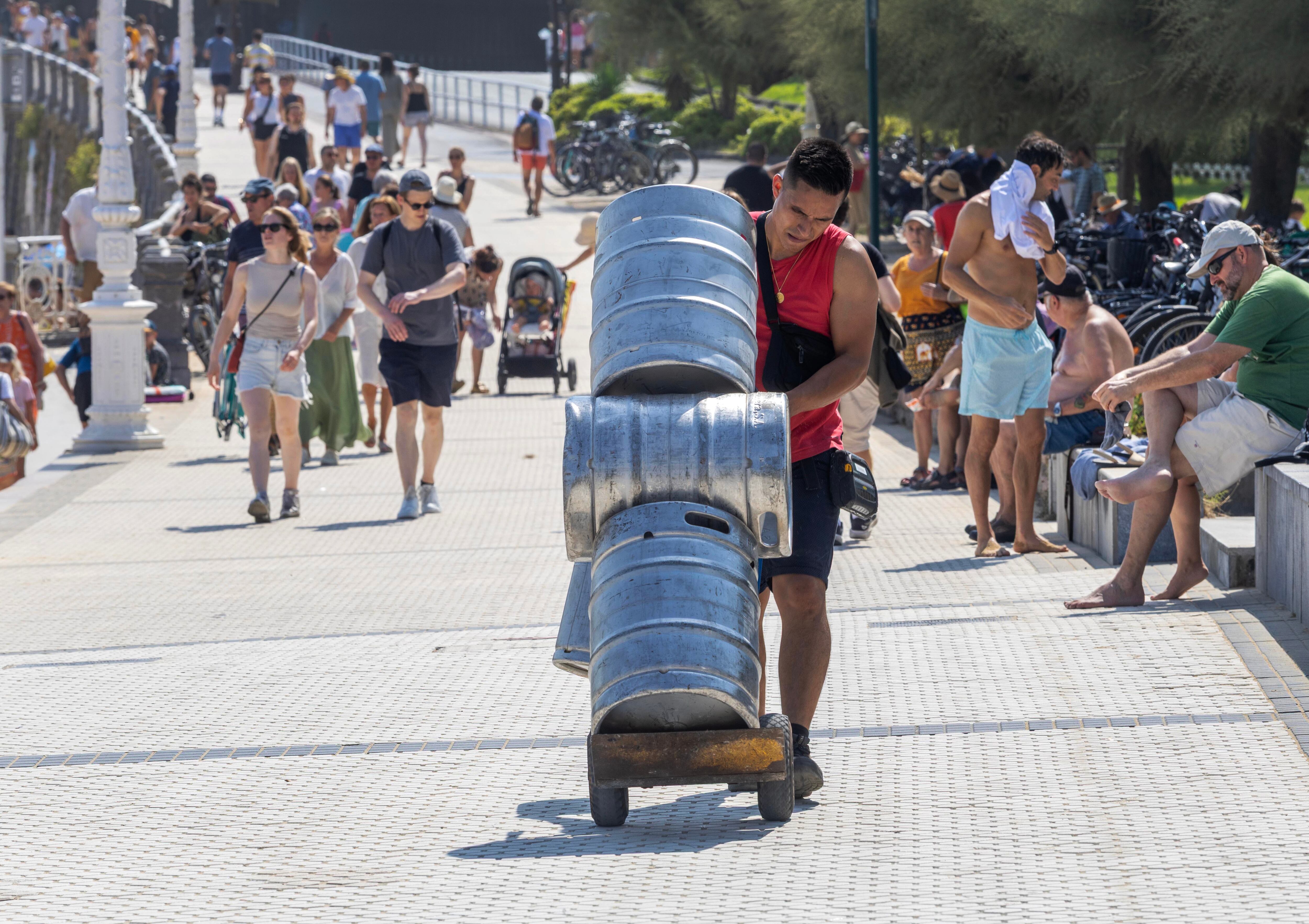 Un trabajador transporta unos barriles durante la ola de calor de agosto de 2025 en San Sebastián.