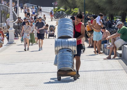Un trabajador transporta unos barriles durante la ola de calor de agosto de 2025 en San Sebastián.