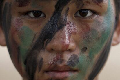 Un niño posa con la cara cubuerta con pintura de camuflaje.