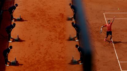 El tenista serbio Novak Djokovic se dispone a sacar. A la izquierda, los recogepelotas.