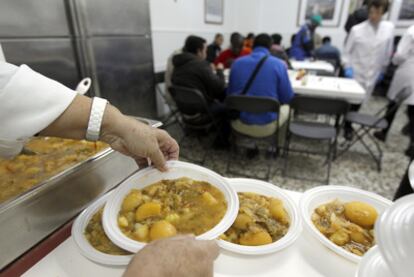 Voluntarios del comedor Cuatro Caminos, en Madrid, sirven comidas.