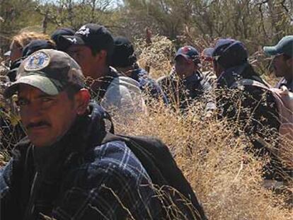 Inmigrantes se agazapan, tras haber logrado cruzar la frontera, ante un helicóptero estadounidense que vigila sus movimientos.