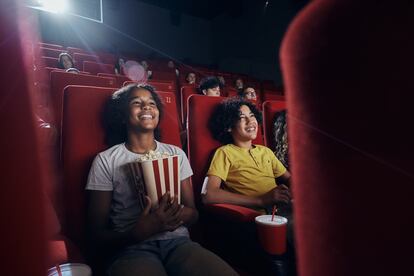 Happy little friends enjoying in movie projection at theatre.