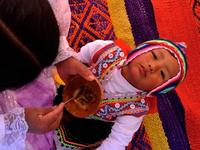 Lidia Dueñas le da de comer a su hijo en el rincón de juegos que tiene en su casa en Lucre (Quispicanchi, Cuzco, Perú).