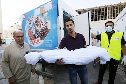 Un hombre traslada un cadáver a una furgoneta de helados por la falta de espacio en la morgue del hospital de los Mártires de Al-Aqsa de Deir al Balah, en la franja de Gaza, este sábado. 