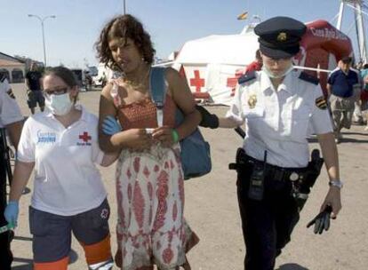 Una voluntaria de la Cruz Roja y una policía conducen a una <i>sin papeles</i> que llegó el viernes a Dénia.