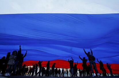 Un grupo de personas sostiene una bandera nacional de Rusia durante las celebraciones del segundo aniversario de la anexin de la regin de Crimea a Rusia, en la plaza Roja de Mosc.