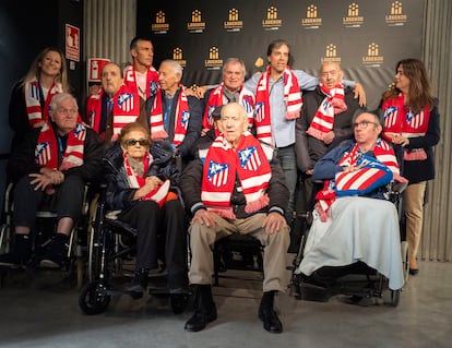 El presidente de la Asociación de Leyendas del Atlético de Madrid, Roberto Solozábal, con camiseta celeste y bufanda, posa junto a los participantes de los talleres en la visita a LEGENDS.