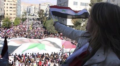 Una mujer ondea una bandera siria desde su balcón.