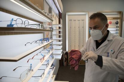 Un trabajador limpia las gafas colocadas en la vitrina de una óptica de Madrid.