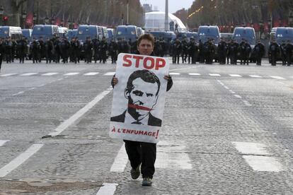 Un manifestante sujeta un cartel con la imagen del presidente francés, Emmanuel Macron, durante la protesta en los Campo Elíseos en París.