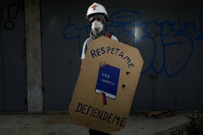 Manifestante segura um escudo feito com uma peça de madeira, com uma representação da Constituição venezuelana. ‘Quero uma Venezuela melhor e Maduro tem de sair. Há gente esfomeada demais e crianças vivendo nas ruas’.