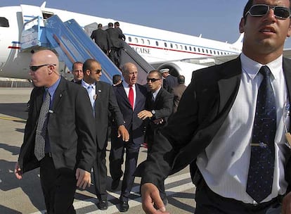 Los guardaespaldas protegen al primer ministro israelí, Ehud Olmert, mientras Sarkozy (al fondo) sube al avión también escoltado por agentes.