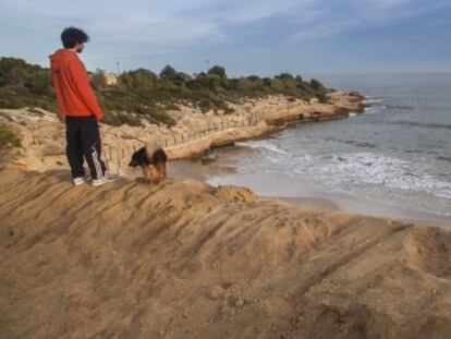 Un joven pasea con su perro por la playa de l&#039;Atmetlla de Mar.