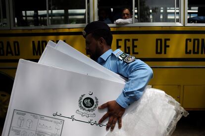 Un oficial de policía carga materiales electorales en un centro de distribución antes de las elecciones generales en Islamabad (Pakistán). 