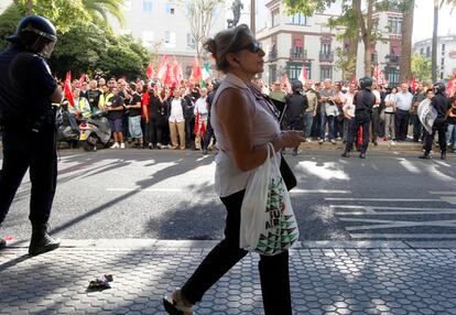 Una cliente de El Corte Inglés sale del establecimiento del centro de Sevilla frente a los piquetes y entre policías.