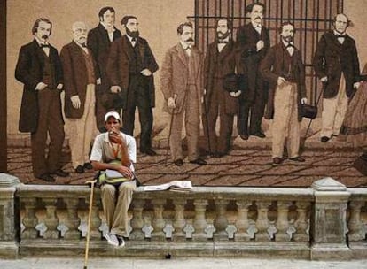 Un cubano fuma un cigarrillo de espaldas a un mural en La Habana.