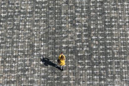 Una mujer toma una foto en la plaza de la Ciudad Vieja de Praga, donde se han dibujado miles de cruces en el pavimento para conmemorar el primer aniversario desde la muerte del primer paciente checo de coronavirus.