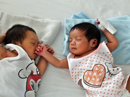 Dos bebés duermen en una cama en la llamada 'fábrica de bebés' de Manila.