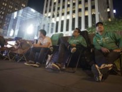 Varias personas esperan en la puerta de la primera tienda de Apple en Nueva York la llegada de los nuevos productos del gigante tecnológico.