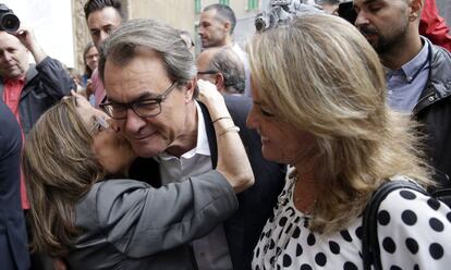 El presidente de la Generalitat y número cuatro en las listas de Junt pel Si, Artur Mas, acompañado de su esposa , Helena Rakosnik,d., es saludado por una simpatizante a su llegada al colegio electoral.