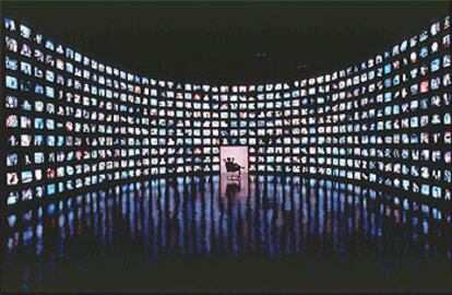 Una persona sentada frente a 500 aparatos de televisión conectados a 500 diferentes canales.