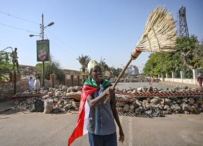 Un manifestante sudanés agita una escoba frente a una barricada improvisada frente al cuartel general del ejército, en la capital Jartum.