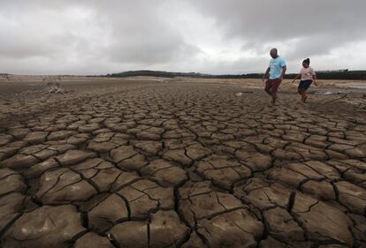 Una familia se abre camino a través del barro en una sección seca de la presa Theewaterskloof, cerca de Ciudad del Cabo, Sudáfrica, el 20 de enero de 2018. La presa, que suministra la mayor parte del agua potable de Ciudad del Cabo, es actualmente peligrosamente baja a medida que la ciudad se enfrenta al Día Cero, previsto para el 11 de mayo. Si para entonces no ha llovido, se cerrarán los grifos de la ciudad.