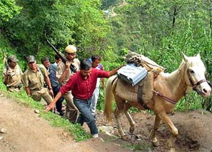 Agentes electorales escoltados trasladan una urna electrónica por la selva de Sepibosti (noreste de India).