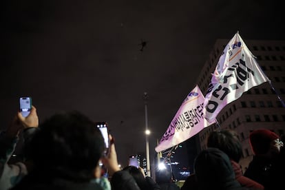 La gente agita pancartas, sobrevolados por helicópteros militares, en Seúl.