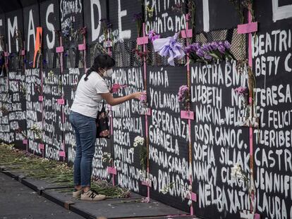 Una mujer pinta una cruz en la valla instalada en el Palacio Nacional en Ciudad de México, el día de hoy.