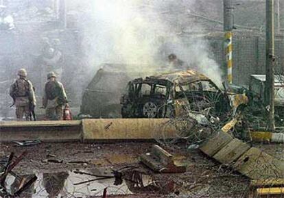 Varios soldados inspeccionan los vehículos destrozados por la explosión, en los que han muerto calcinadas muchas de las víctimas.