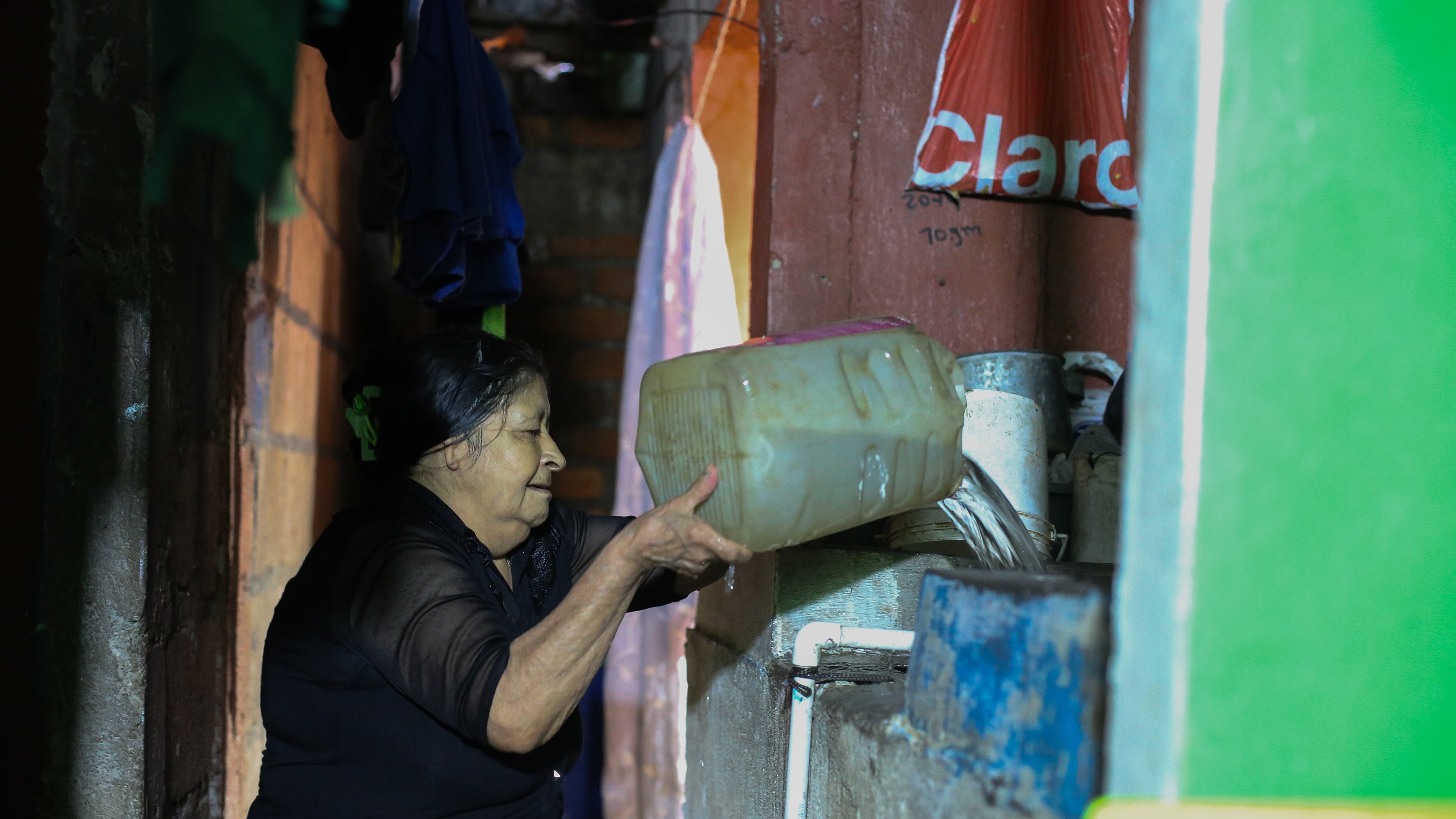 Suyapa Alvarenga traspasa agua desde un barril hacia su pila tras recolectarla de la lluvia, en Tegucigalpa, el 7 de octubre.