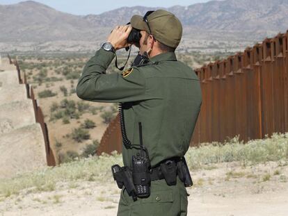 Un agente de la patrulla fronteriza vigila la valla en Nogales, por donde miles de personas tratan de cruzar de México a EE UU.