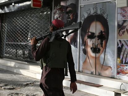 Un guerrillero talibán pasa delante de un salón de belleza en Kabul donde las imágenes de las mujeres se han censurado con aerosol negro, este miércoles.