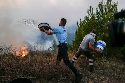 Un oficial de policía y un voluntario trabajan para apagar las llamas en Cascais (Portugal), este martes. 