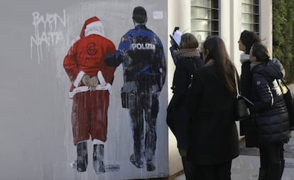 Cuatro transeuntes observan el mural de Tvboy en Milán, el lunes 10 de diciembre.