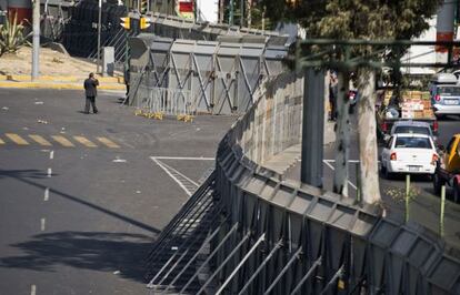 Un hombre camina junto a las vallas que han sido colocadas para resguardar el Congreso mexicano en vísperas de la investidura de Enrique Peña Nieto.