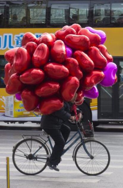 Un comerciante porta en bici decenas de globos con forma de corazón