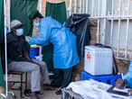 A military personnel inoculate a dose of SinoVac vaccine to a  citizen at a mobile clinic in Emganwini township, Bulawayo, Zimbabwe on 3 August 2021.  Zimbabwe National Army is conduct a community outreach program to assist citizens to get vaccinated. (Photo by Zinyange Auntony / AFP)