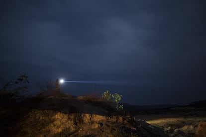 Um homem com uma lanterna procura sinal para o celular no alto de um morro em Areinha (MG).