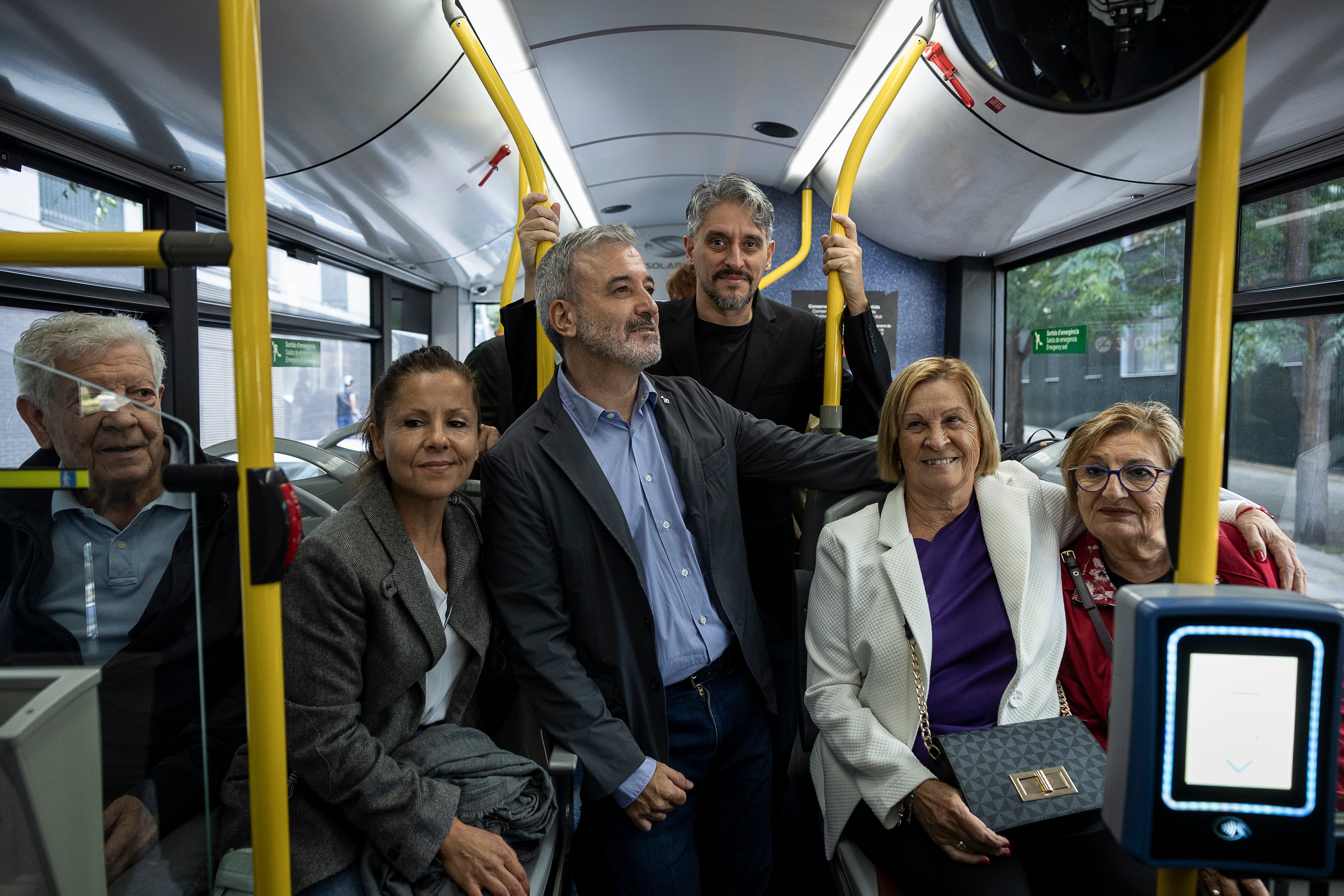 Joana Vital, nieta de Manolo, Jaume Collboni y Marcel Barrena, junto a vecinos de Torre Baró en un autobús este sábado.