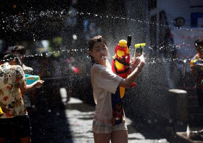 En el primer día del Songkran, en el que Bangkok ha alcanzado una temperatura de unos 30ºC, jóvenes tailandeses y turistas se han lanzado a las calles a mojar y ser mojados —muchos de ellos, como la chica de la imagen, con sus móviles protegidos con fundas impermeables—.