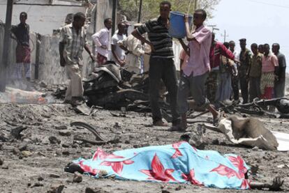 Un cadáver tendido junto a restos de edificios quemados en el lugar del atentado de ayer en Mogadiscio.