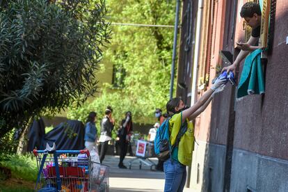 Una voluntaria reparte bienes de primera necesidad a través de las ventanas en Milán (Italia).