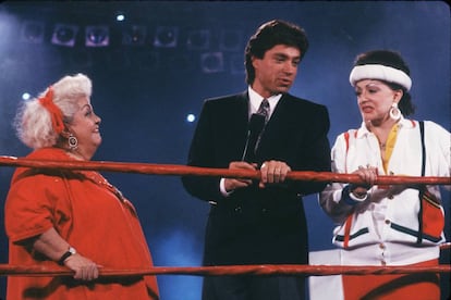 Jackie Stallone (a la derecha de la imagen) con el presentador Ross Shaffer (centro) en 1988. Eran sus tiempos de presentadora de 'GLOW', el 'show' de lucha libre femenina que triunfaba en Estados Unidos y también pudimos ver en Telecinco.