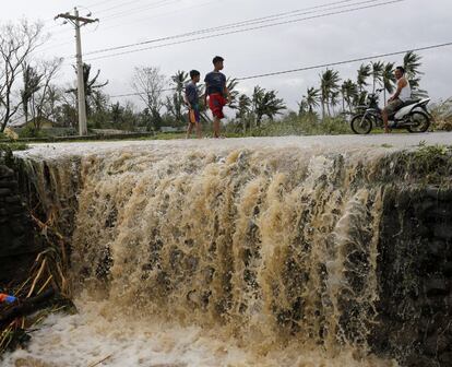 Varios niños cruzan una calle inundada por el paso del tifón Heima en la ciudad de Abulog, provincia de Cagayan (Filipinas). Al menos cuatro personas han muerto en Filipinas a causa del tifón, que golpeó hoy con fuertes vientos e intensas lluvias el norte del país, donde miles de personas tuvieron que ser evacuadas.