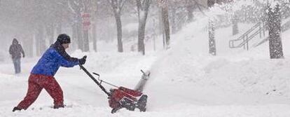 Una mujer intenta quitar la nieve de la carretera en Wauwatosa (Estados Unidos).